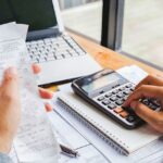 Young man using calculator and calculate bills in home office.