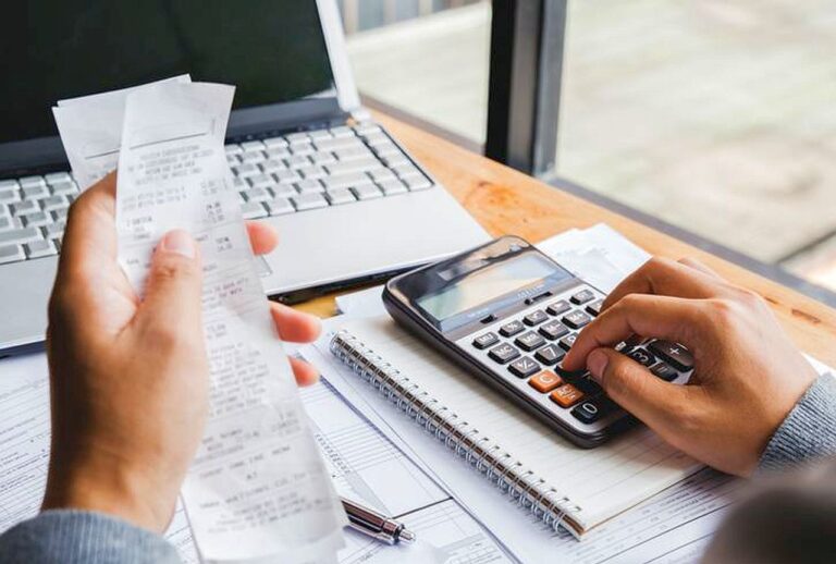 Young man using calculator and calculate bills in home office.