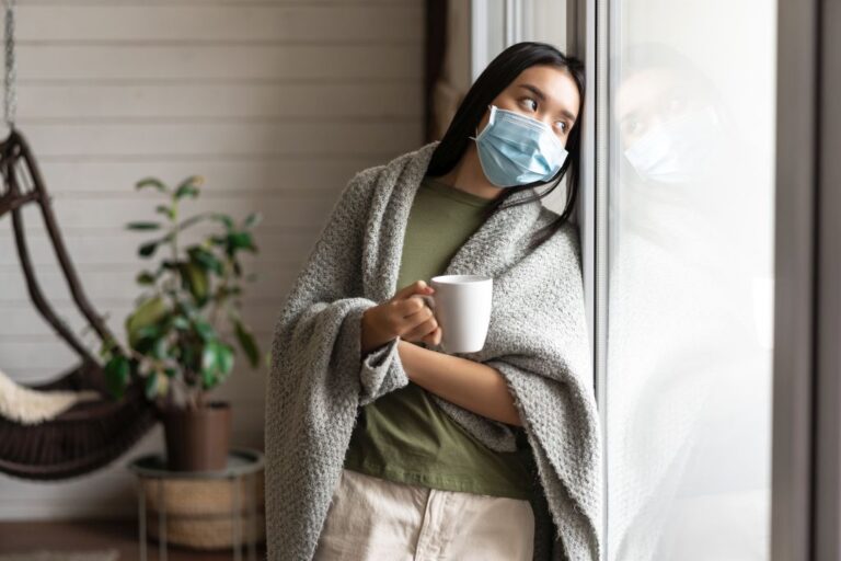 Asian girl in medical face mask, yearning go outside, being sick with covid 19 and staying on self quarantine in her house