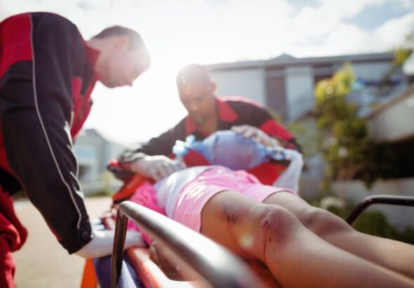 Paramedic giving oxygen to injured girl at accident spot